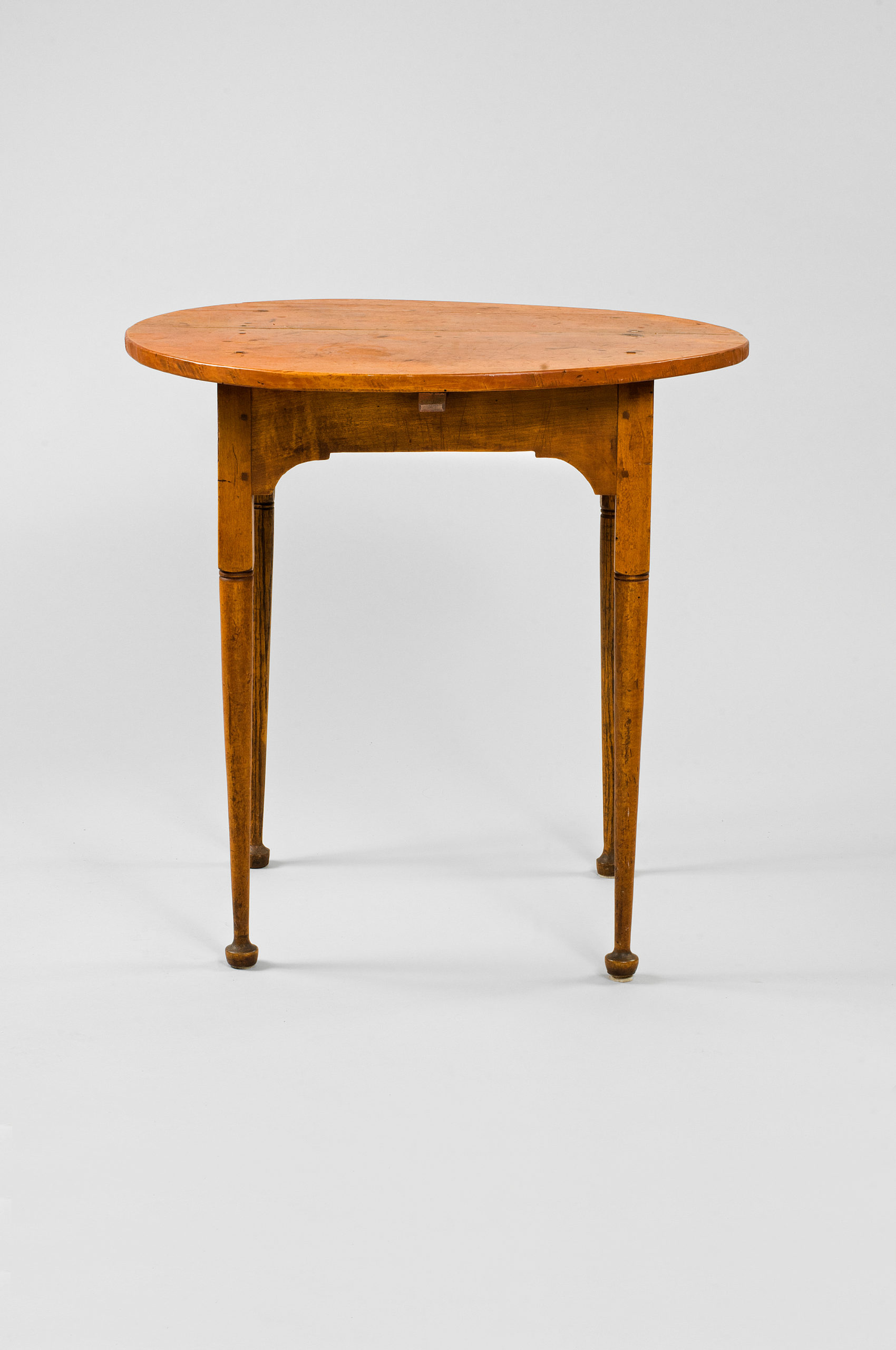 Small, four-legged, wooden table made out of maple with a warm, slightly orange finish.