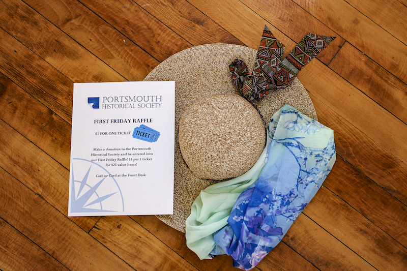 Image of a straw sunhat and a blue adn green lightweight scarf against a wooden background