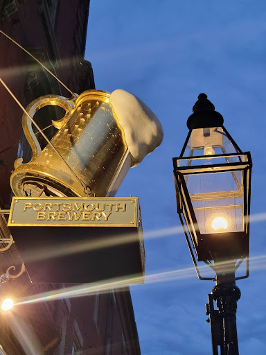 Portsmouth Brewery sign with a beer stein on it next to an old fashioned street lamp. 