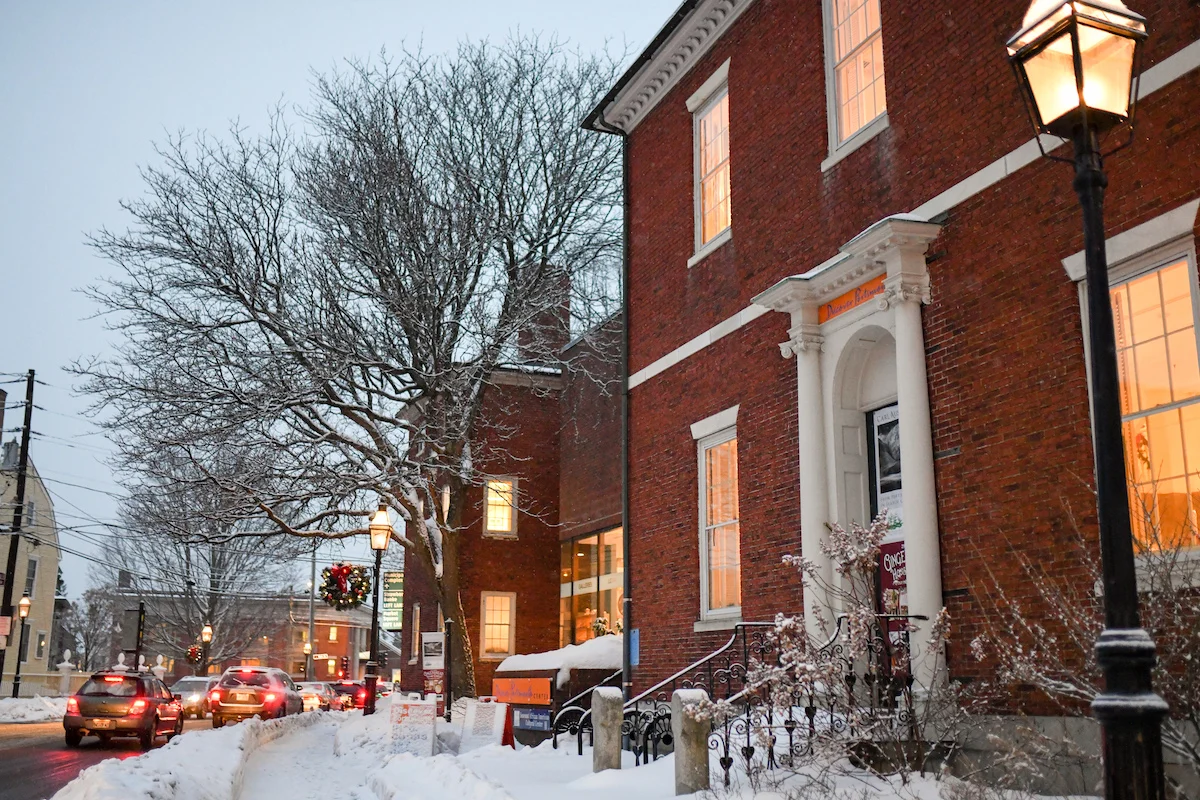 Early evening outside a two-story brick building with an old-fashioned iron street lamp in the front of the image.