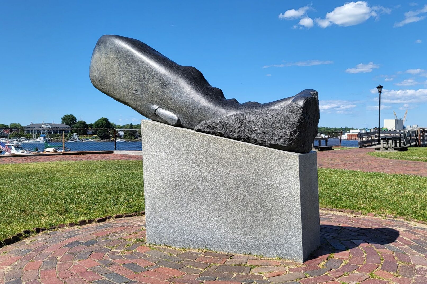 Black granite sculpture of a sperm whale rising out of the water.