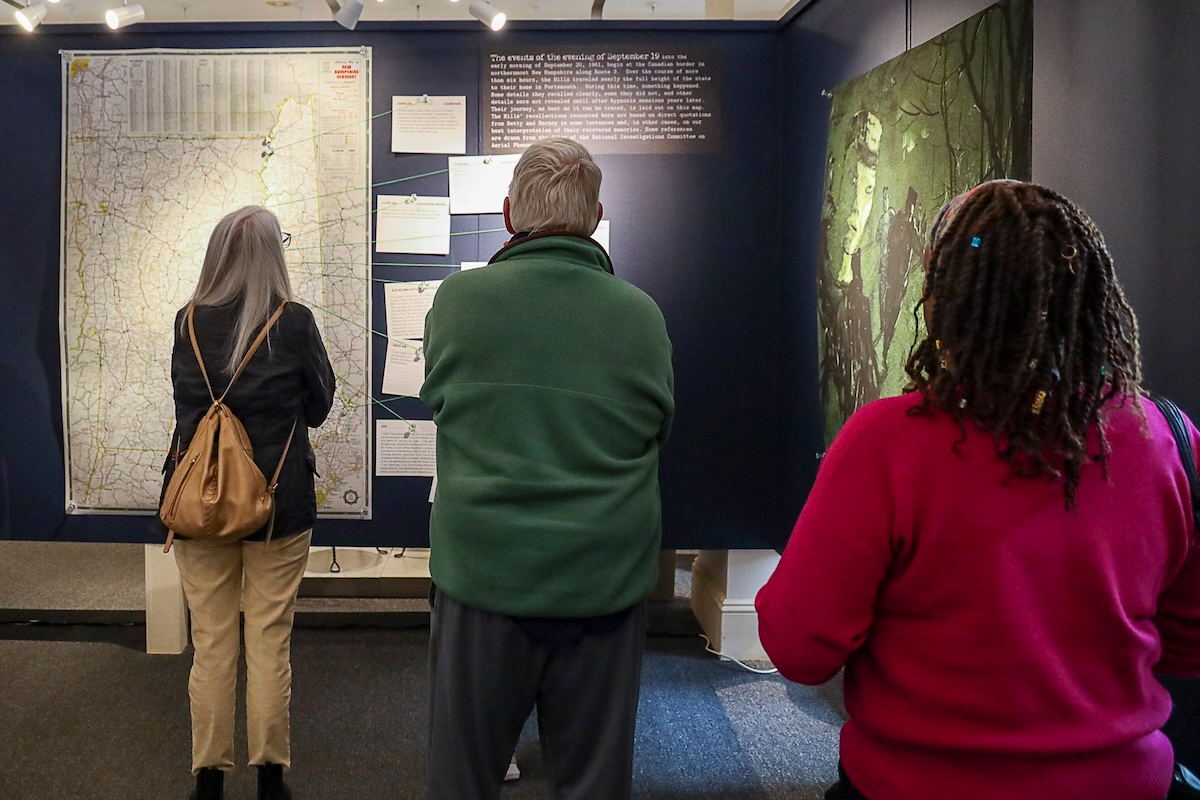 Portsmouth Historical Society visitors examine the map charting the Hills' journey south through New Hampshire, marking off stops and sightings along the route.